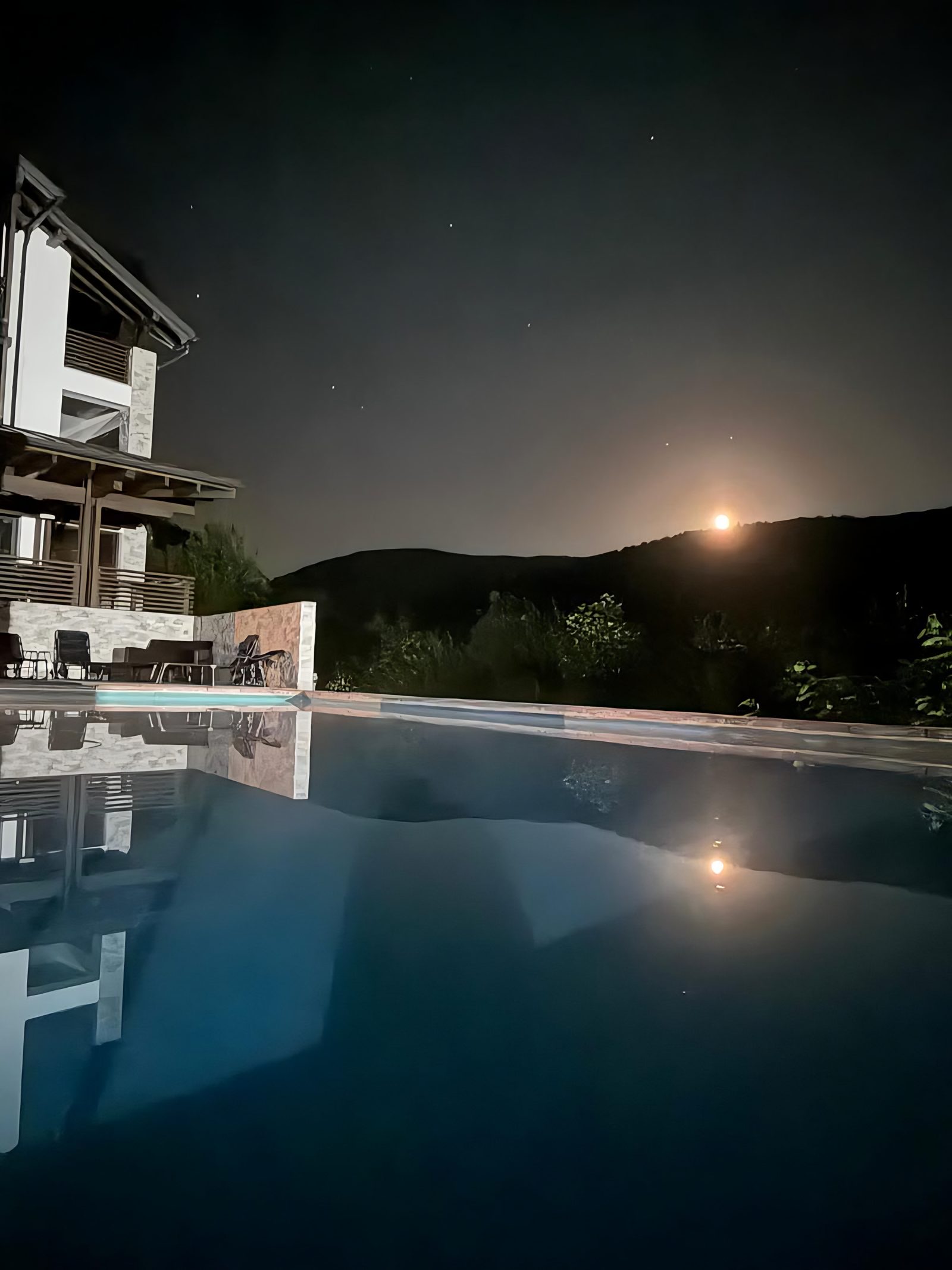 Piscina la lumina lunii, cu vila reflectată în apă